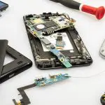 téléphone démonté montrant ses composants internes et batterie lors d'une réparation
