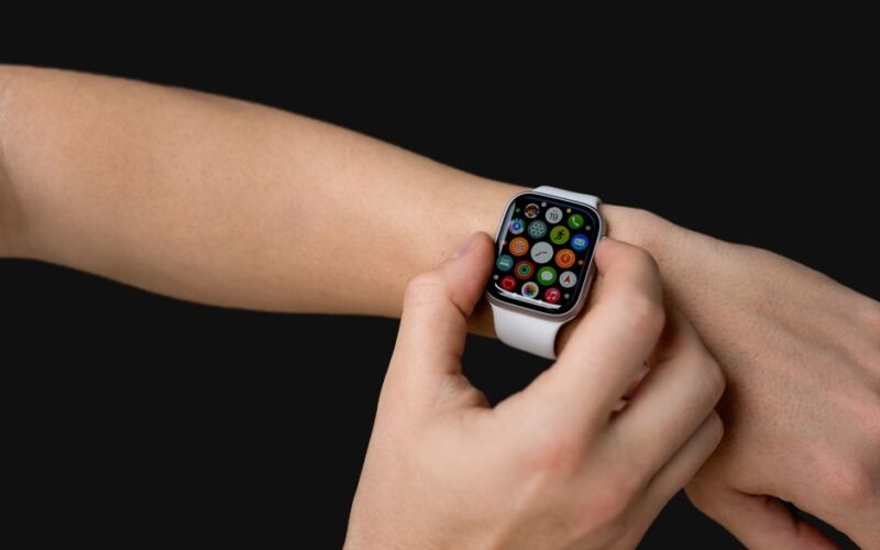 Close-up of hands using a smartwatch with app icons visible, representing modern technology.