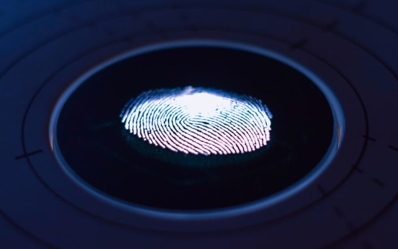 A glowing fingerprint on a dark circular scanner surface with concentric lines